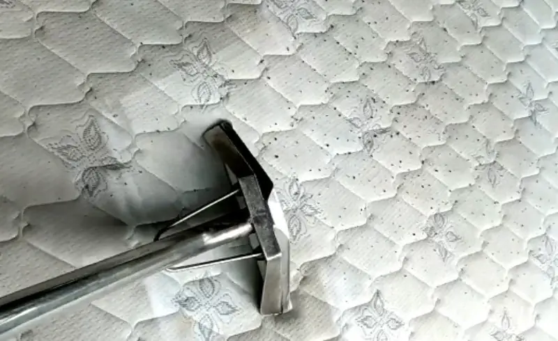 Extraction tool lifting dust and debris from a mattress surface
